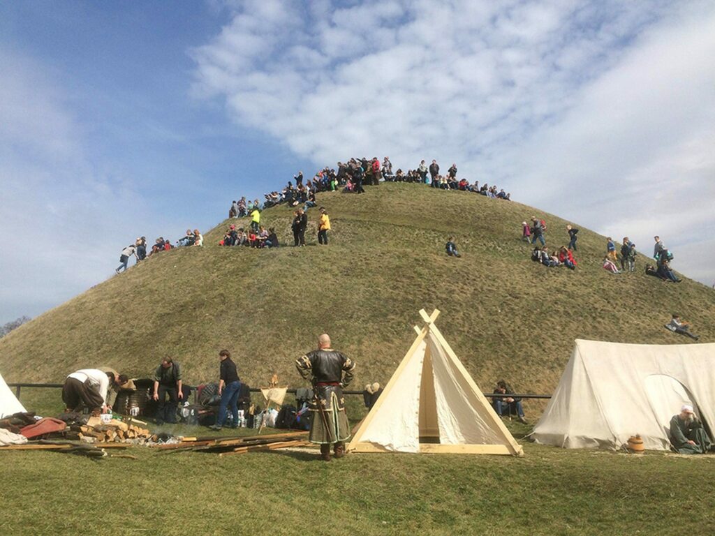 A historical event with tents at the foot of a mound